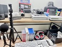 Overall view showing consoles, controllers, keyboard, mouse, microphone, headphones, game discs and accessories on shelving