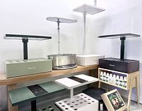 Seven countertop hydroponic units on table with nutrient bottles visible
