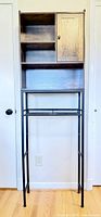 Full front view of tall over-the-toilet cabinet showing metal frame and wood shelving.