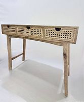 Front view of desk showing three cane drawers and leg structure