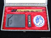 Open brocade box showing brushes, ink stone, ink stick and porcelain pot