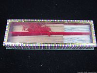 Closed striped box showing two folded fans through clear lid