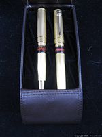Two gold-tone pens inside brown leather case
