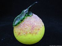 Front view of yellow glass fruit with green leaf and stem