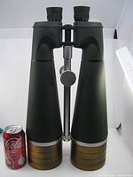 Front view of full binoculars beside soda can for scale