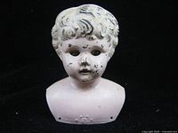 Front view of painted metal Minerva doll head showing facial features, glass eyes and paint wear