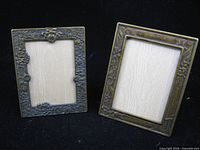 Front view of both brass picture frames showing floral borders and openings