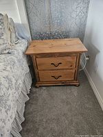 Front view of solid pine end table beside bed