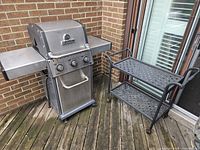 Broil King gas BBQ next to black metal rolling cart