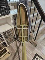 Underside of collapsible ironing board showing green metal frame and mesh surface