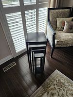 Four black metal nesting tables nested together