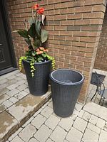 Two tapered round resin wicker planters, one planted, one empty