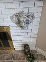 Front view of plaster lion head plaque mounted on brick fireplace