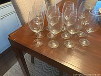 12 clear stemmed wine glasses grouped on wooden table