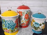 Three Pioneer Woman stoneware canisters showing sizes and floral patterns