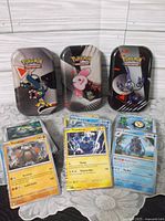 Three Pokémon tins and stacks of cards shown
