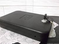 closed black portable handgun safe with key inserted in lock