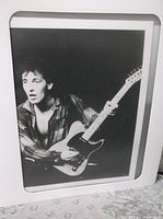 Matted black and white photo of guitarist holding electric guitar