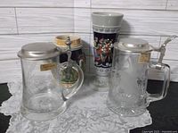 Group view of four steins showing materials, lids and decorative designs