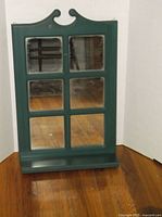 Full view of green wooden mirror with shelf