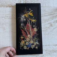Full view of black wooden plaque with pressed flowers