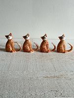 Four small orange tabby bone china cat figurines lined up