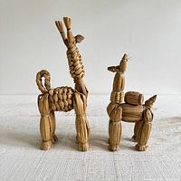 Front view of both straw llama figurines