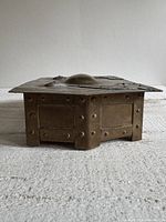 Front view of brass box showing riveted sides and hammered dome lid