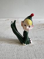 Front view of ceramic pixie elf figurine showing facial features, pose and paint wear