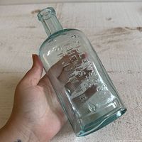 Bottle held in hand showing embossed lettering