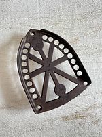 Top view of cast iron trivet showing star spokes and circular holes