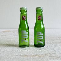 Front view of both green glass 7 Up miniature bottle shakers upright