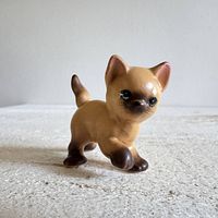 Front view of small Siamese pottery cat figurine on surface