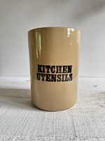 Front view of beige stoneware crock showing \"KITCHEN UTENSILS\" text