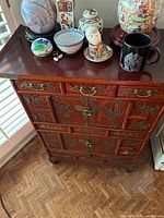 Front view of carved wood cabinet showing drawers and brass hardware