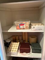 Cabinet shelves showing multiple boxes of candles, cube candles, jar candle