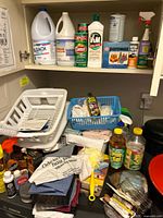 Overview of shelf showing multiple cleaning products, dish rack, cloths and bottles