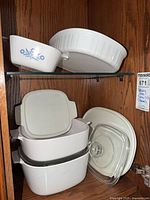 Cabinet view showing Cornflower casserole, round baker, stack of square dishes with lids, glass lid