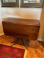 Table closed showing overall form, pedestal legs, brass feet