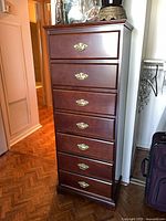 Full front view of tall seven-drawer lingerie dresser showing cherry finish and brass pulls