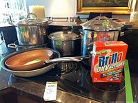 Group shot of all cookware and Brillo box on countertop