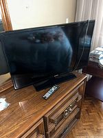 Front view of Samsung 32-inch TV on dresser with remote in foreground