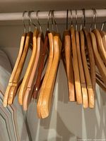 Row of light and medium wood hangers on closet rod