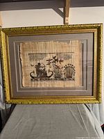 Full view of framed papyrus artwork on stand