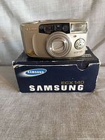 Front view of Samsung ECX 140 camera resting on original box