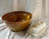Two nested Arcopal mustard swirl bowls and Pyrex Butterfly Gold butter dish