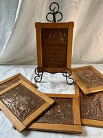 Six framed copper plaques, one displayed upright