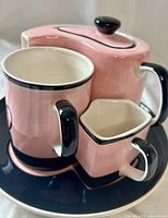 Stacked view of teapot, mug, creamer on plate