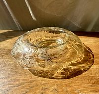 Angled view showing floral etching, rolled rim and yellow tint