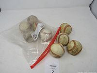 Nine used baseballs, six in a clear zip-top bag and three outside